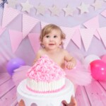 bolo rosa e bebe sorrindo em seu ensaio com bolo