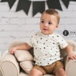 bebe sentado em sofa no cenario tijolos brancos